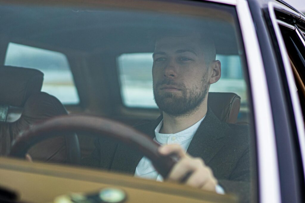 a bearded man driving a car